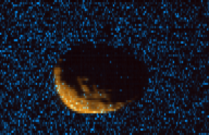 Phobos as observed by MAVEN's Imaging Ultraviolet Spectrograph. Orange shows mid-ultraviolet (MUV) sunlight reflected from the surface of Phobos, exposing the moon's irregular shape and many craters. Blue shows far ultraviolet light detected at 121.6 nm, which is scattered off of hydrogen gas in the extended upper atmosphere of Mars. Phobos, observed here at a range of 300km, blocks this light, eclipsing the ultraviolet sky. On the dayside of Phobos, some bright blue pixels indicate that the moon is reflecting far-UV light, which will allow for the first time a measurement of Phobos' reflectivity at this wavelength, adding to an extremely limited database of measured far-UV reflectivity of small bodies in the solar system. (Courtesy CU/LASP and NASA)