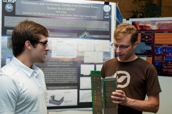 An REU student explains his cubesat power system design to a scientist during the final poster session.