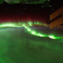 Bright green "waves" of light above Earth, with part of the International Space Station in view.