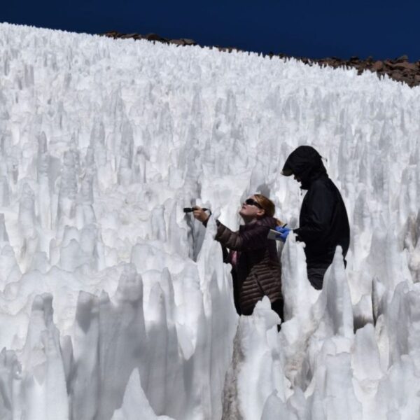 Two CU Boulder graduate students take measurements among the icy pinnacles of the penitente field on the tallest active volcano on Earth, Ojos del Salado.