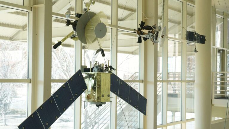 Some of the many models built by Phil Evans that hang from the ceiling of LSTB, including a model of the Galileo spacecraft showing the partially deployed high-gain antenna, which is made of netting. (Credit: LASP