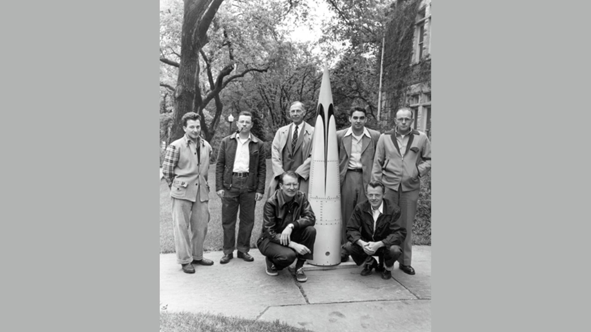 Some of the founding members of the Upper Air Laboratory at CU (UAL, now CU/LASP) and an ogive that was produced for the two unknown scientists standing at the far right. The tripod base contains and supports a turntable that could simulate a an Aerobee’s spin- stabilzed fuselage. And the base of the ogive contains the despin motor that would compensate for the Aerobee’s rotation. Credit: LASP/Ball